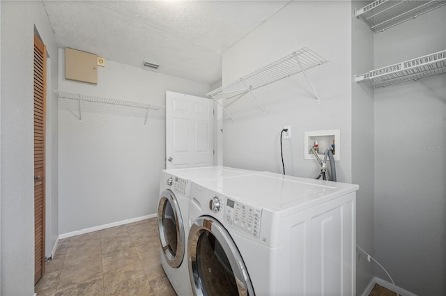 laundry room with a textured ceiling and washing machine and clothes dryer