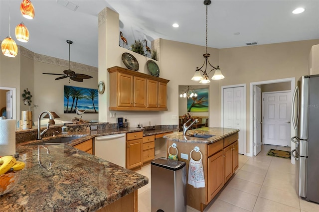 kitchen with dishwasher, stainless steel fridge, sink, and a kitchen island with sink