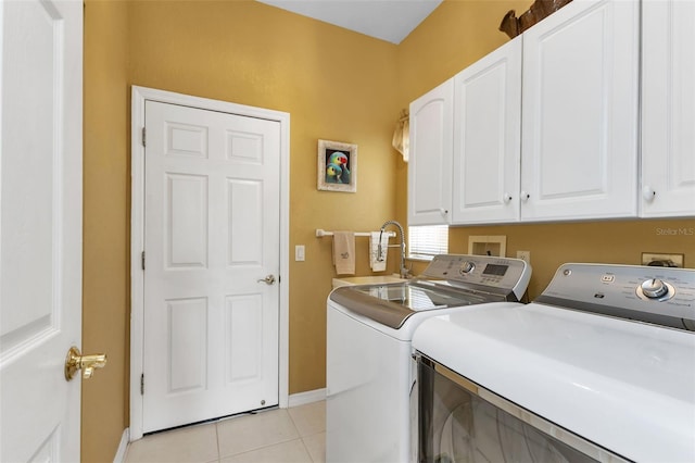 laundry area with washer and dryer, light tile patterned floors, and cabinets