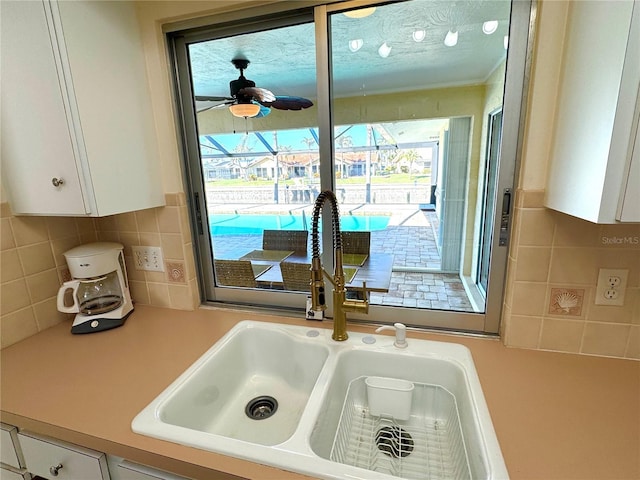 details featuring white cabinets, ceiling fan, sink, and tasteful backsplash