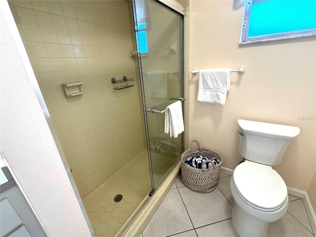 bathroom featuring toilet, tile patterned floors, and a shower with door