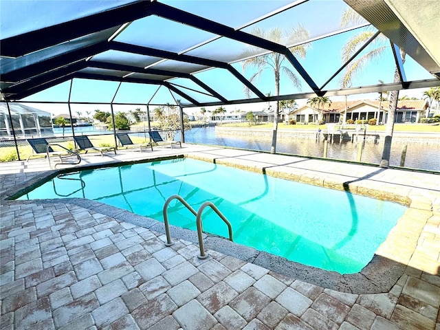 view of pool featuring glass enclosure, a water view, and a patio