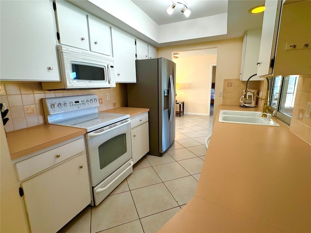 kitchen with white appliances, sink, decorative backsplash, light tile patterned flooring, and white cabinetry