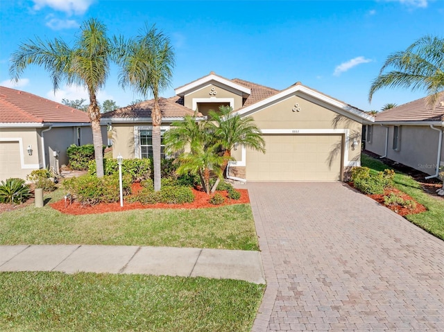 view of front of home featuring stucco siding, a front lawn, decorative driveway, and a garage