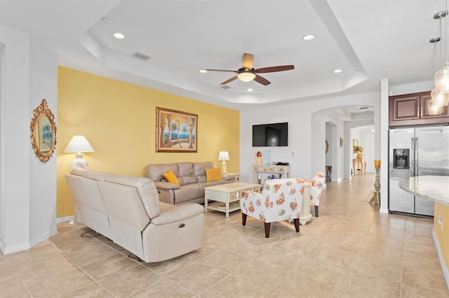 living room featuring light tile patterned floors, a tray ceiling, and ceiling fan