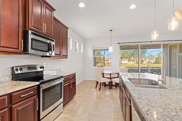 kitchen featuring light stone counters, sink, hanging light fixtures, and appliances with stainless steel finishes