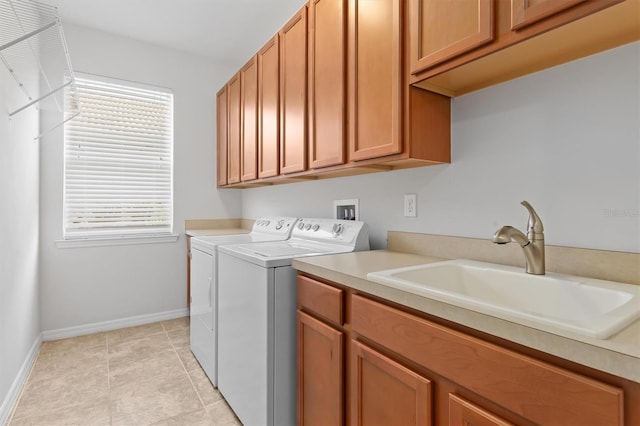 clothes washing area featuring a sink, cabinet space, light tile patterned flooring, baseboards, and washing machine and clothes dryer