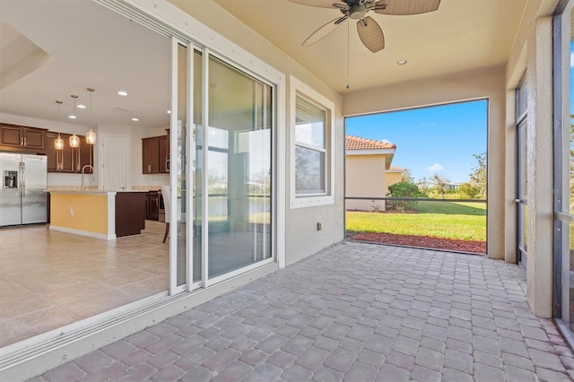 unfurnished sunroom with a sink and a ceiling fan