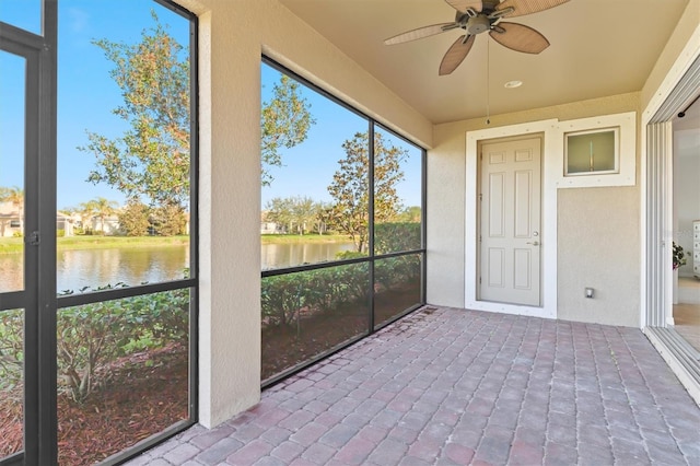 unfurnished sunroom with ceiling fan, a water view, and plenty of natural light