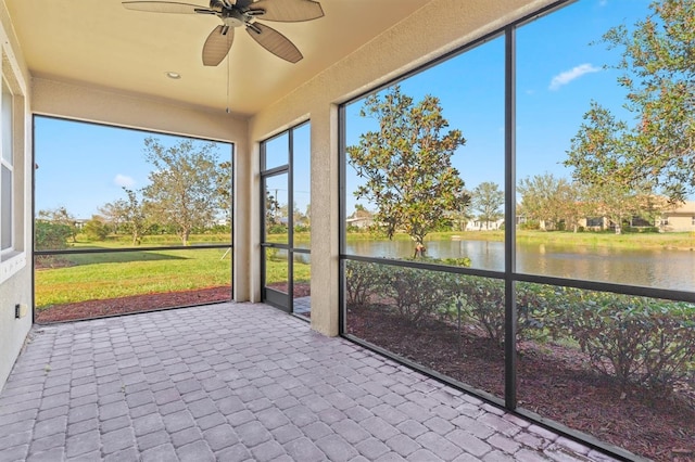 unfurnished sunroom with ceiling fan and a water view