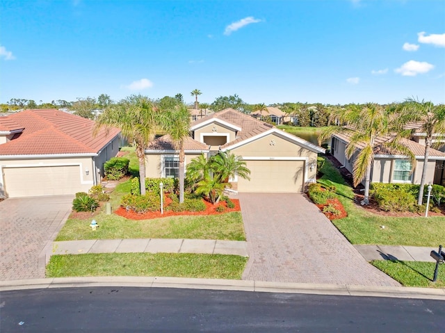 mediterranean / spanish home with an attached garage, stucco siding, a front lawn, a tiled roof, and decorative driveway