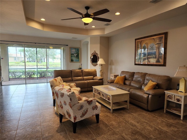 living area with a tray ceiling, recessed lighting, visible vents, and ceiling fan