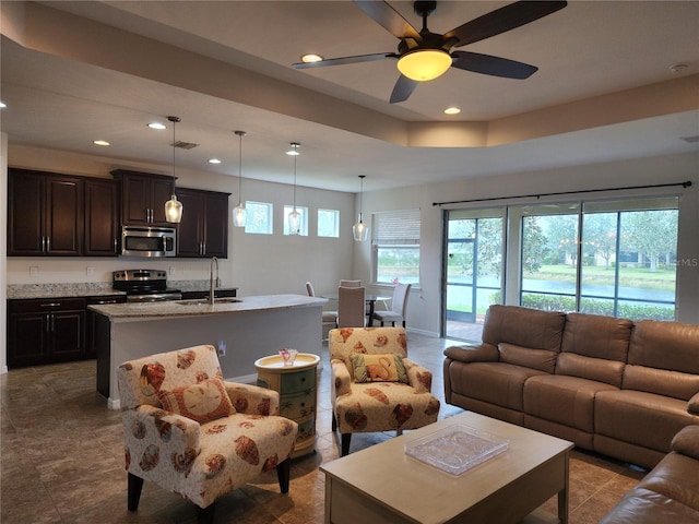 living area with recessed lighting, visible vents, a raised ceiling, and ceiling fan