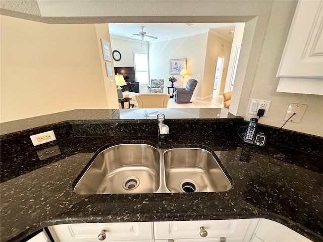 details featuring dark stone counters, sink, crown molding, ceiling fan, and white cabinetry