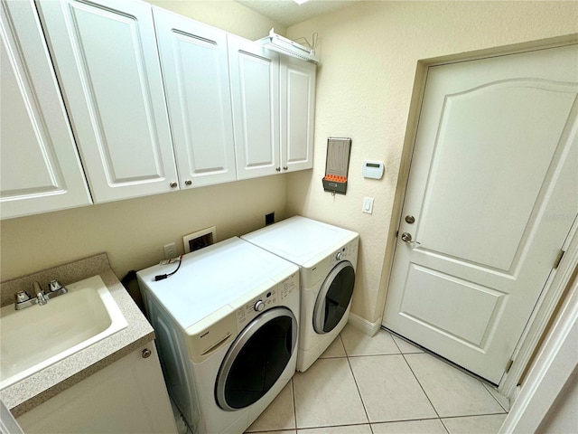 washroom with cabinets, light tile patterned floors, separate washer and dryer, and sink