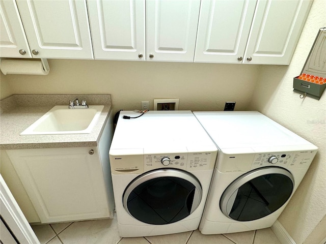 laundry area with cabinets, light tile patterned floors, washing machine and clothes dryer, and sink