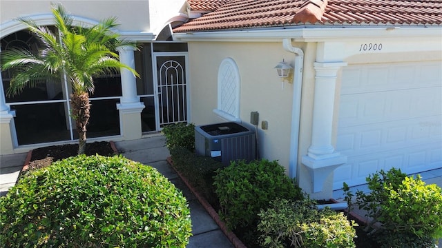 doorway to property with a garage and central AC