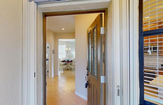 hall featuring tile patterned flooring and a notable chandelier