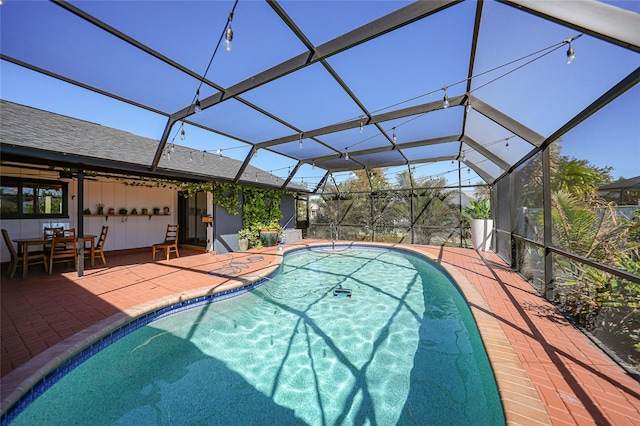 view of swimming pool featuring glass enclosure and a patio