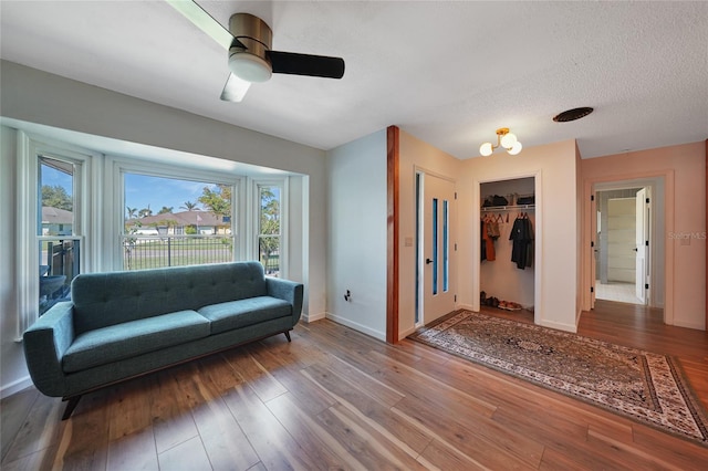 living room featuring a textured ceiling, hardwood / wood-style flooring, and ceiling fan