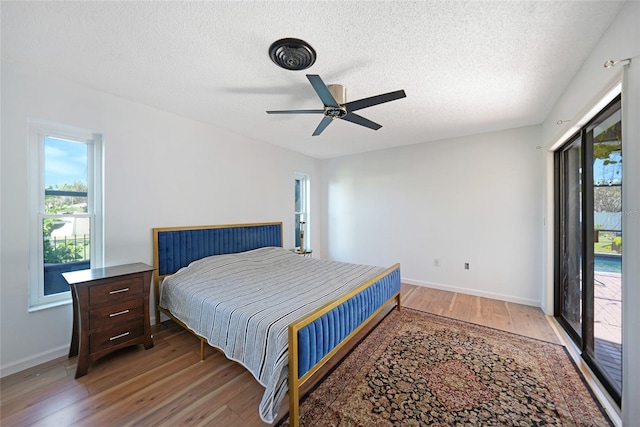 bedroom featuring access to outside, ceiling fan, a textured ceiling, and hardwood / wood-style flooring