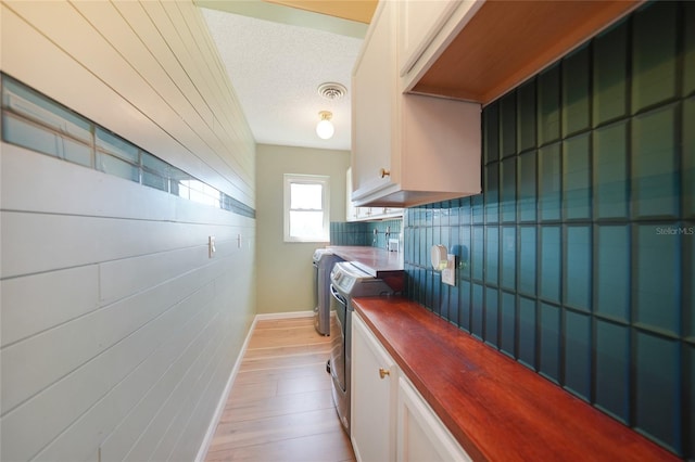 kitchen featuring tasteful backsplash, white cabinetry, a textured ceiling, and light wood-type flooring