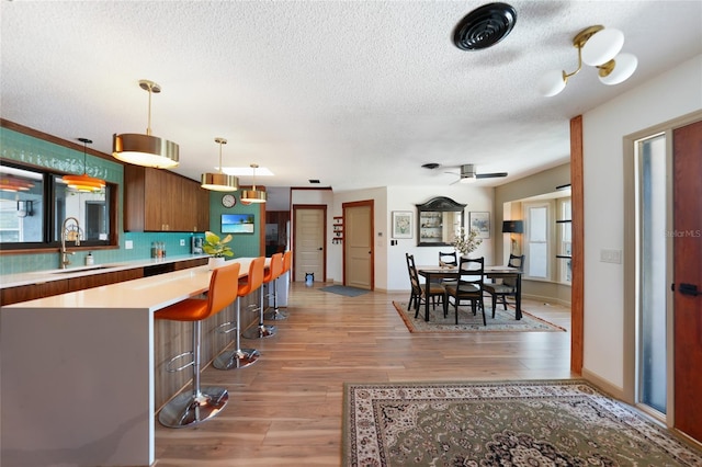 kitchen featuring a breakfast bar, light countertops, light wood-type flooring, and a sink