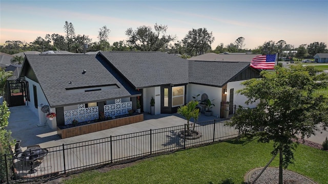 view of front of property with concrete driveway, stucco siding, fence private yard, and a shingled roof