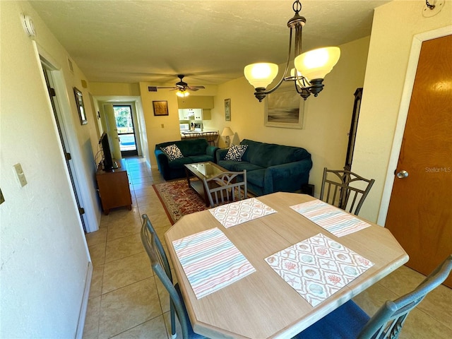 dining area with ceiling fan with notable chandelier, light tile patterned floors, and a textured ceiling