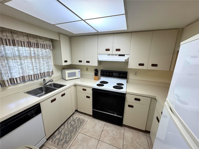 kitchen with white appliances, sink, light tile patterned floors, washer / dryer, and white cabinetry