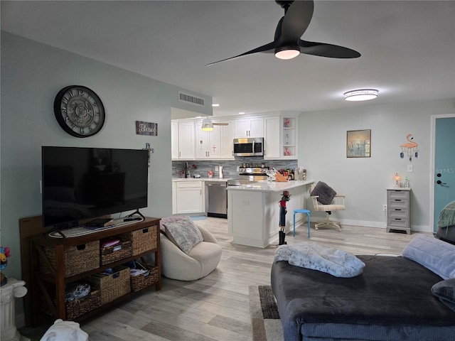 living room with light hardwood / wood-style flooring and ceiling fan