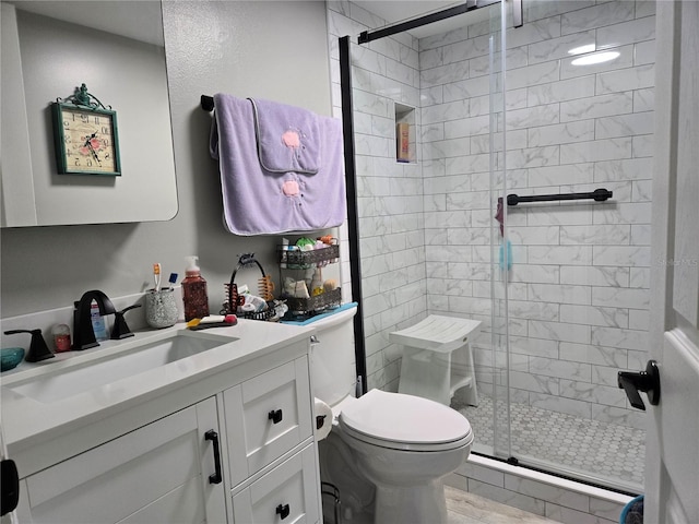 bathroom with an enclosed shower, vanity, toilet, and wood-type flooring