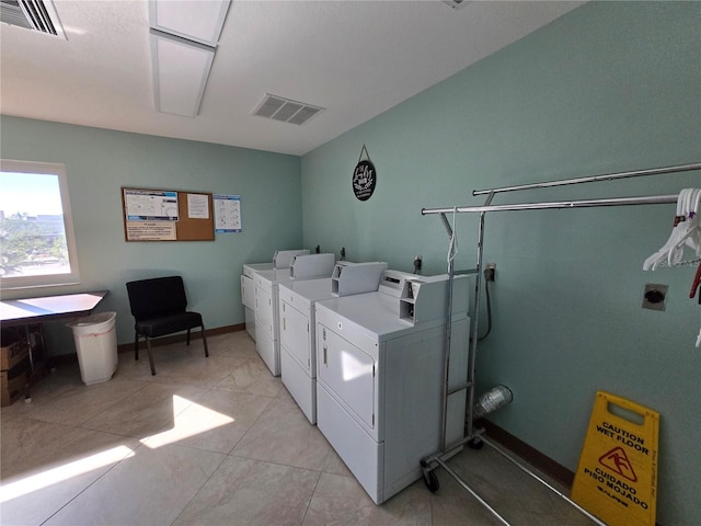 clothes washing area featuring washing machine and dryer and light tile patterned floors