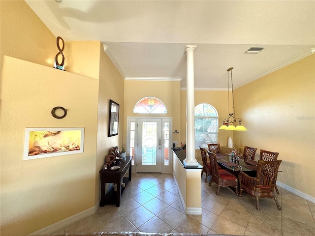 entrance foyer with tile patterned flooring, ornate columns, ornamental molding, and a notable chandelier