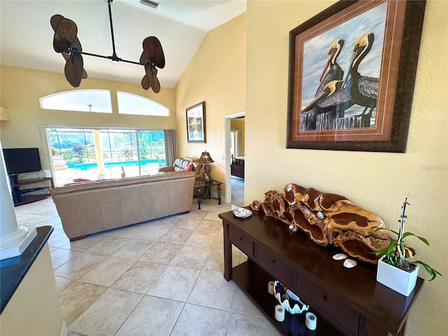 living room featuring decorative columns, light tile patterned floors, and vaulted ceiling