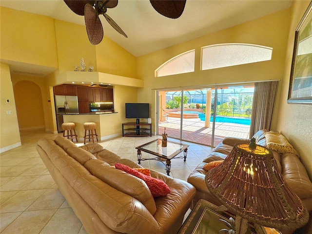 tiled living room with ceiling fan and high vaulted ceiling