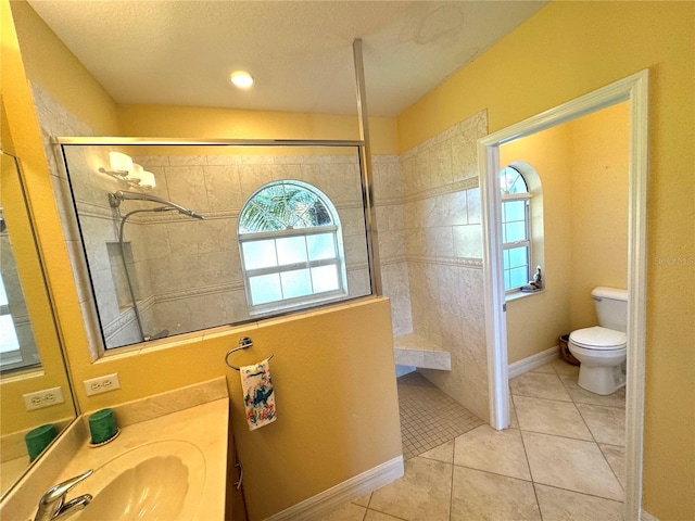 bathroom with tile patterned floors, vanity, toilet, and tiled shower