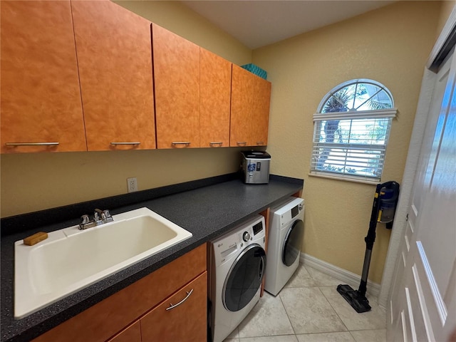 clothes washing area with washer and clothes dryer, sink, light tile patterned floors, and cabinets