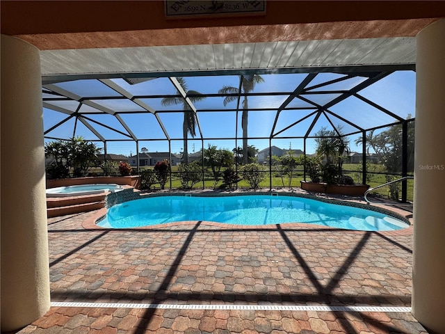 view of pool featuring glass enclosure, an in ground hot tub, and a patio area