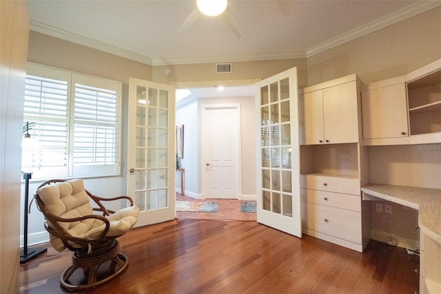 living area with french doors, crown molding, built in desk, dark hardwood / wood-style floors, and ceiling fan