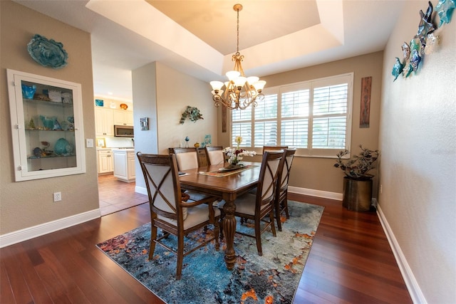 dining area featuring a chandelier, dark hardwood / wood-style flooring, and a tray ceiling