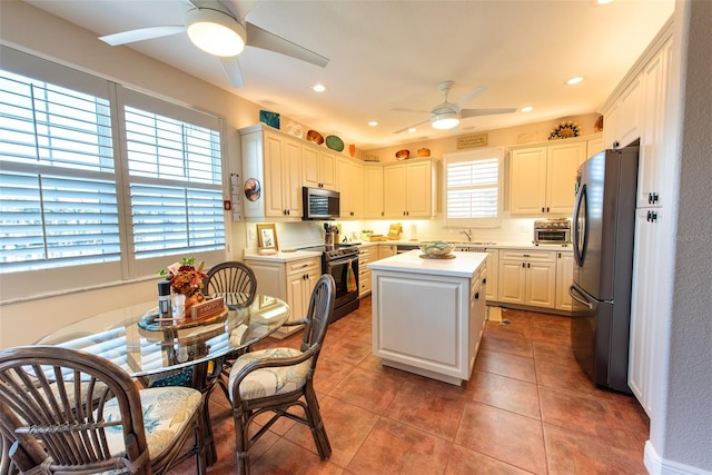 kitchen with a center island, tile patterned floors, ceiling fan, appliances with stainless steel finishes, and white cabinetry