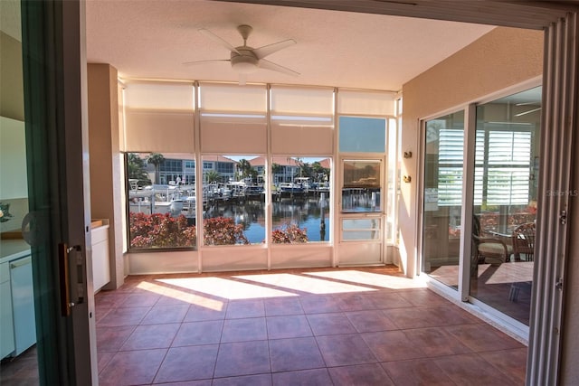 unfurnished sunroom featuring ceiling fan and a water view