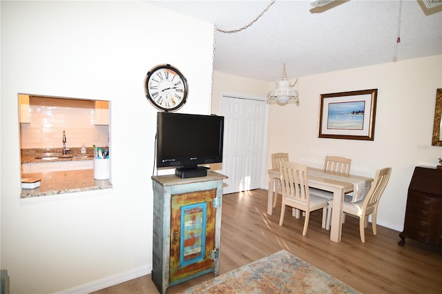 dining space with a textured ceiling, light hardwood / wood-style floors, and sink