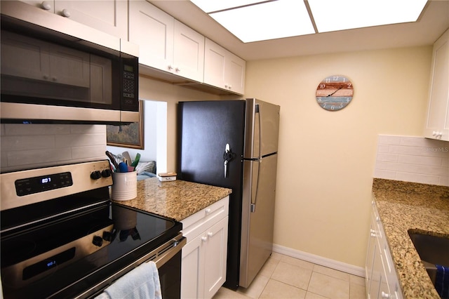 kitchen featuring light stone countertops, backsplash, stainless steel appliances, light tile patterned floors, and white cabinetry