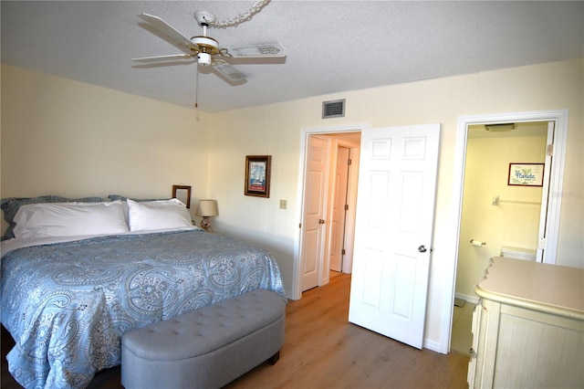 bedroom featuring hardwood / wood-style flooring, ceiling fan, ensuite bathroom, and a textured ceiling