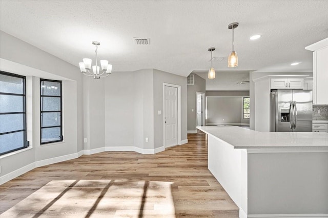 kitchen featuring white cabinetry, stainless steel fridge with ice dispenser, decorative light fixtures, and light wood-type flooring