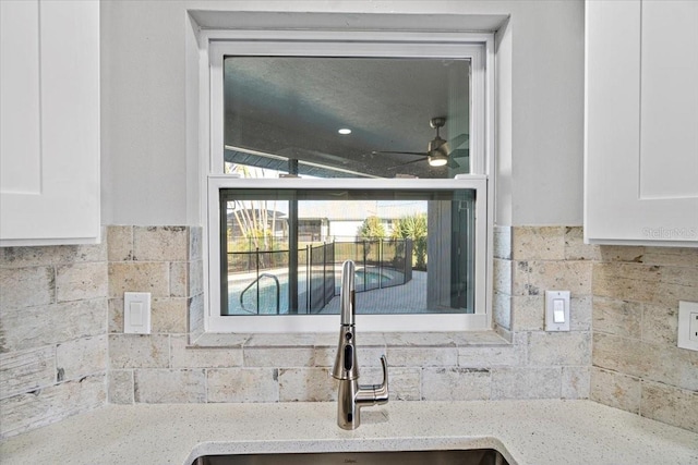 room details featuring light stone countertops, white cabinetry, ceiling fan, and sink