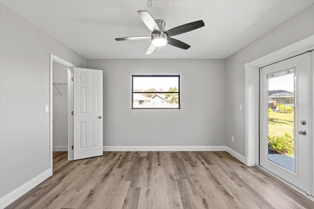 unfurnished bedroom featuring ceiling fan, access to exterior, a spacious closet, light wood-type flooring, and a closet