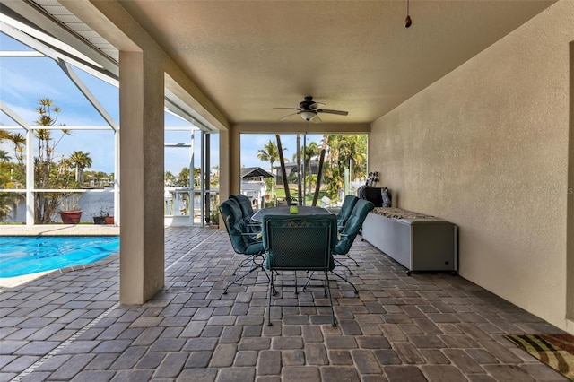 view of patio / terrace featuring a water view, glass enclosure, and ceiling fan